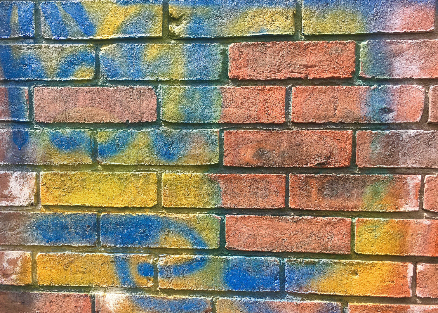 A painted brick wall with multicoloured patterns painted on it. This can be removed with our graffiti removal paint