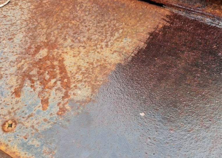 rusted metal surface with treated section ready for paint